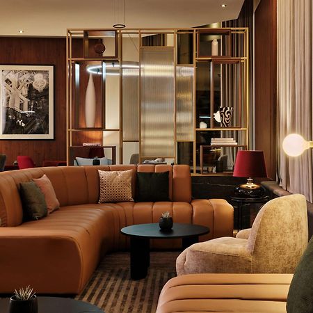Radisson Blu Hotel Cracovia Esterno foto The photo shows a modern and stylish lounge area. It features a curved, multi-colored sectional sofa with a combination of beige, brown, and green upholstery. There are various decorative cushions on the sofa, adding a touch of comfort. In front of t