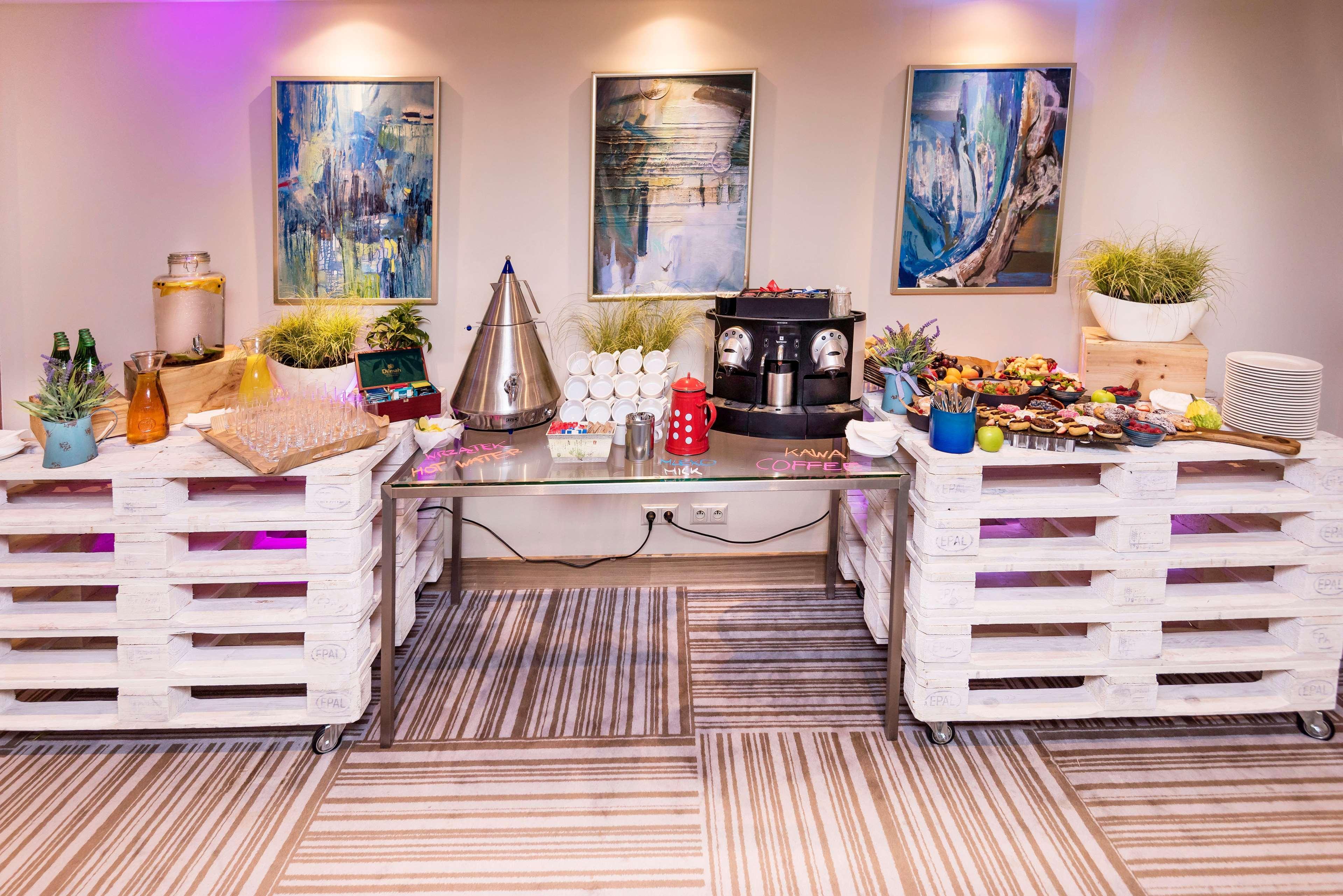 Radisson Blu Hotel Cracovia Esterno foto The image depicts a setup designed for an event or gathering. In the foreground, there are two white pallets used as tables, each adorned with various items. On the left, there are beverages in bottles and a decorative container, alongside a small co