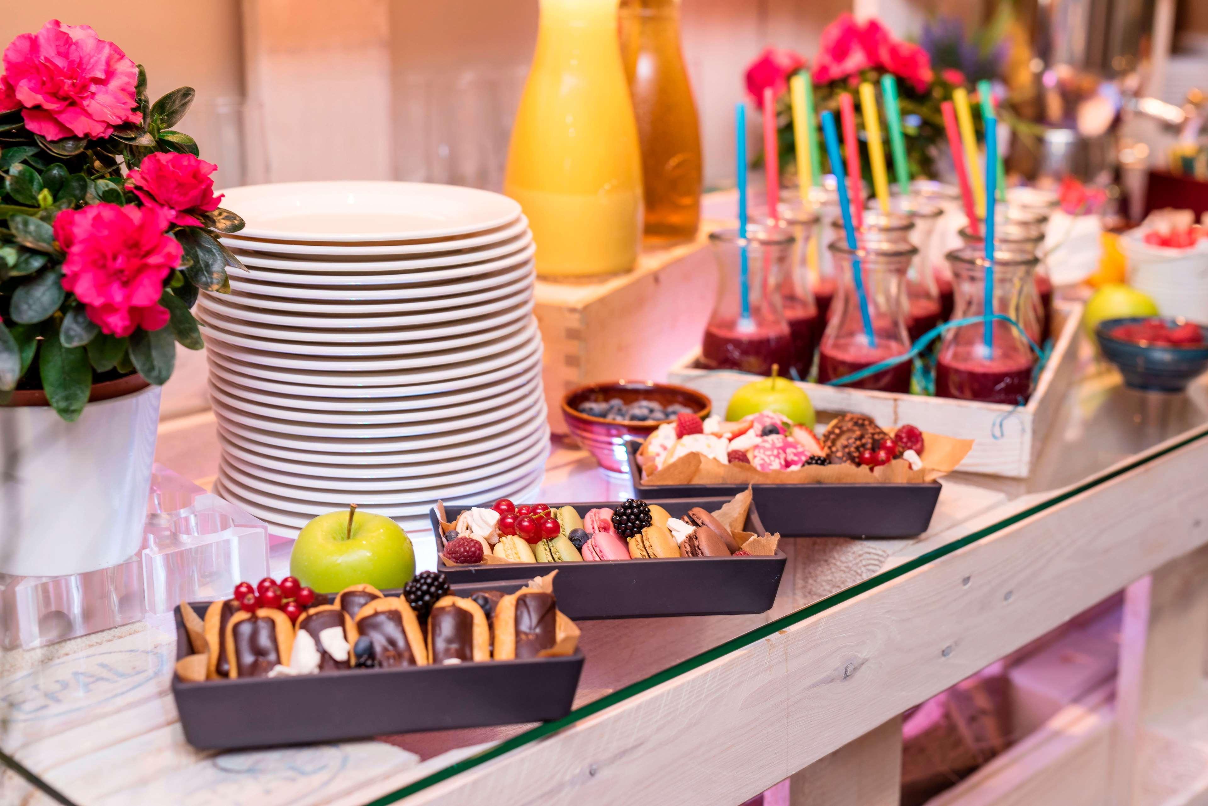 Radisson Blu Hotel Cracovia Esterno foto The photo displays a charming buffet setup featuring various food items. In the foreground, there are three trays filled with desserts, including chocolate-covered treats, fruits, and possibly mini pastries. An apple sits among the desserts. Behind t