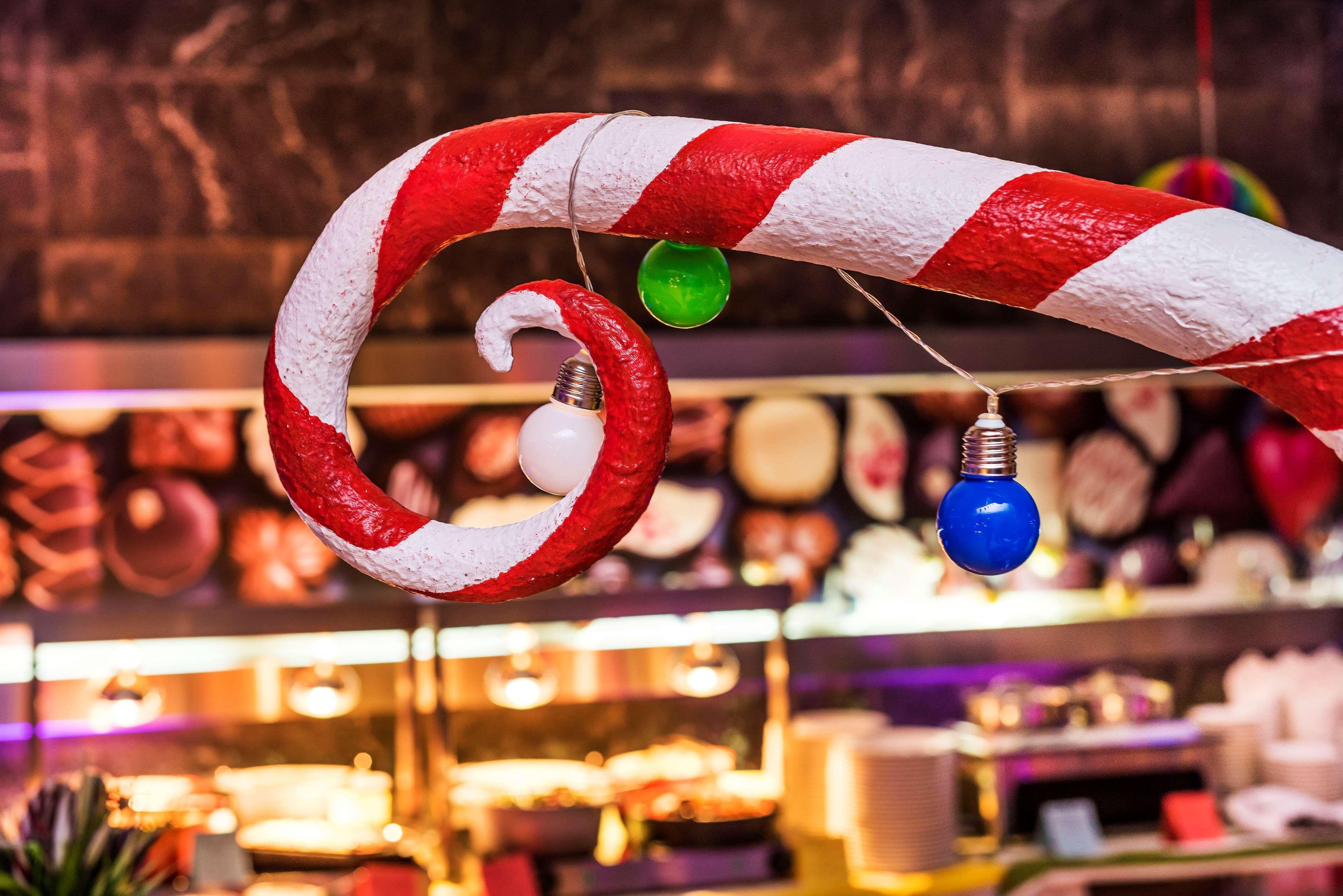 Radisson Blu Hotel Cracovia Esterno foto The photo shows a colorful decoration resembling a candy cane, with red and white stripes. It features a spiral shape, and several light bulbs are hanging from it. The bulbs are in different colors, including green, blue, and white. In the background