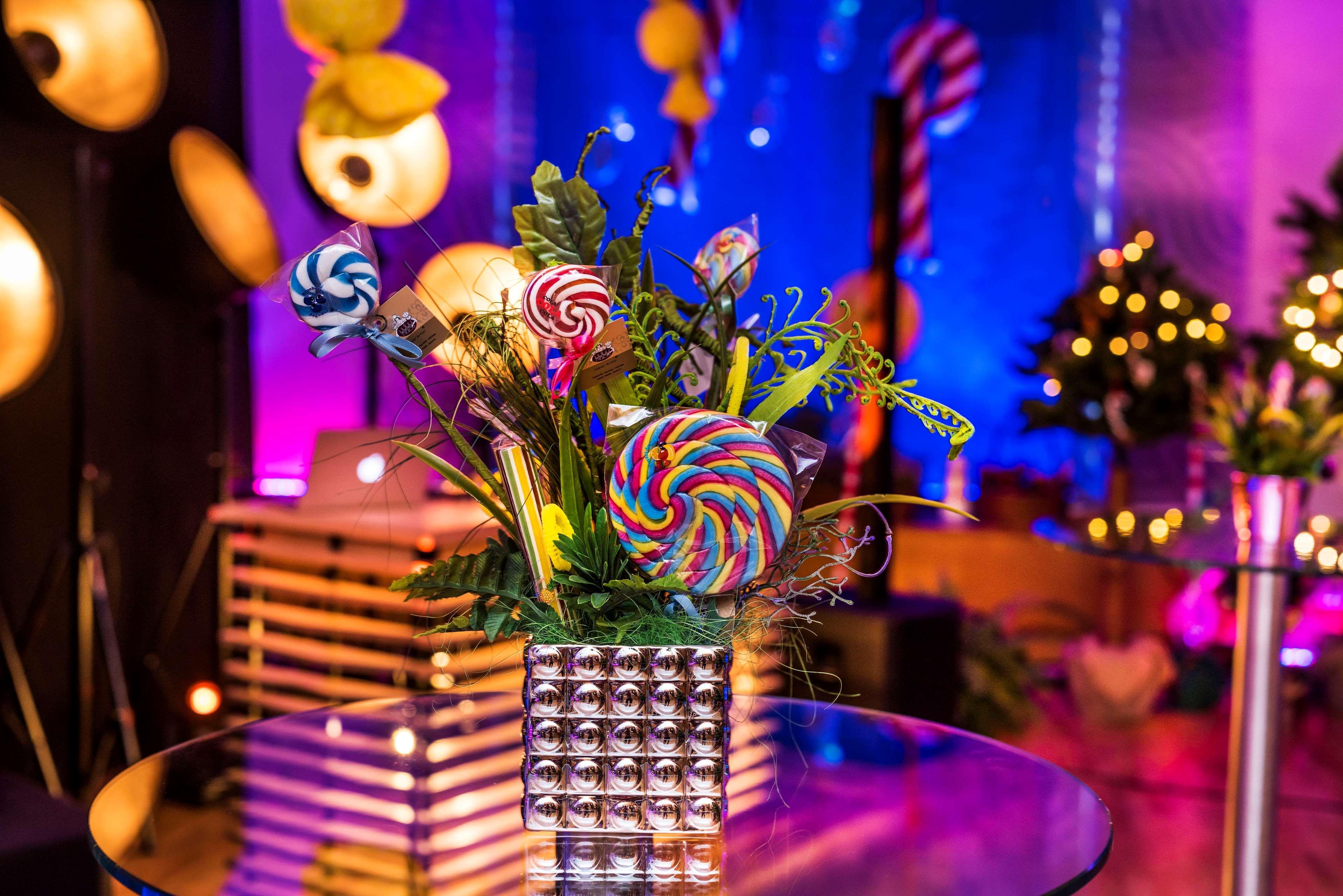 Radisson Blu Hotel Cracovia Esterno foto The photo shows a decorative arrangement featuring colorful lollipops arranged in a shiny metallic vase. The bouquet includes various types of lollipops, particularly one large spiral lollipop with vibrant colors. Surrounding the lollipops are green 
