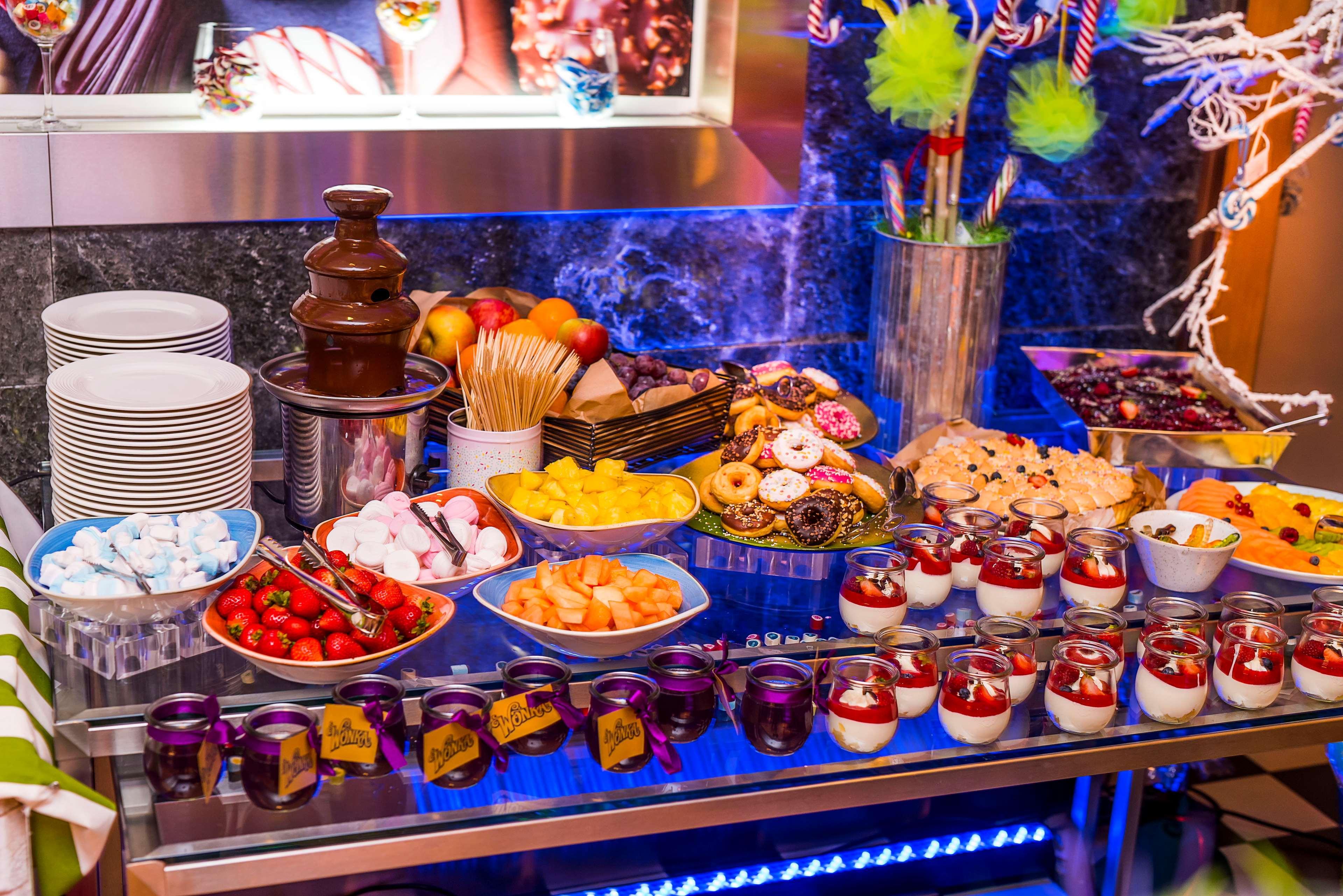 Radisson Blu Hotel Cracovia Esterno foto The photo displays a vibrant dessert buffet with a variety of sweet treats and snacks. There is a chocolate fountain in the center, surrounded by plates of fruits such as strawberries and pineapple. Additionally, there are cookies, donuts, and small 