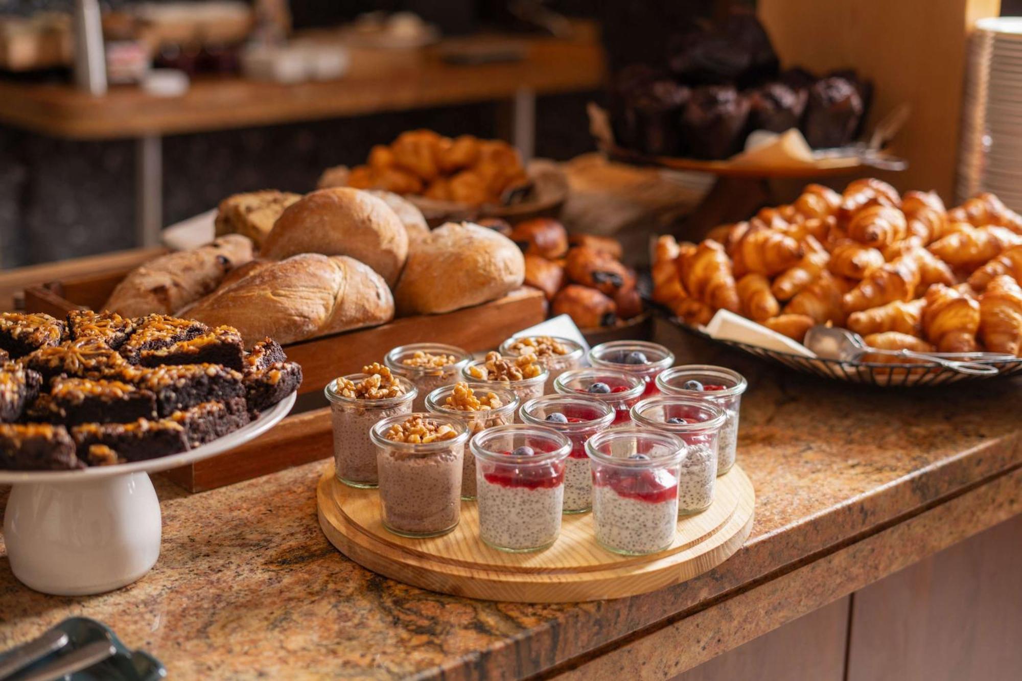 Radisson Blu Hotel Cracovia Esterno foto The photo displays a beautifully arranged breakfast spread featuring a variety of baked goods and desserts. Prominent items include:

- **Breads:** Several types of bread are shown, including round loaves and possibly baguettes.
- **Pastries:** There